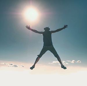 Rear view of woman jumping against sky during sunset