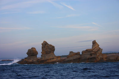 Rock formations in sea against sky