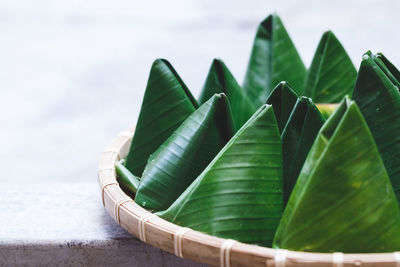 Close-up of sweet food wrapped in banana leaves in containers at table