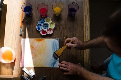 High angle view of man painting paper at wooden table