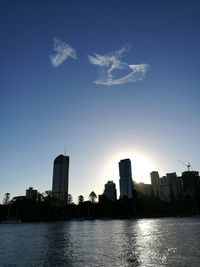 River by buildings against blue sky