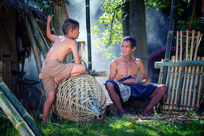 Boy talking with father sitting on field