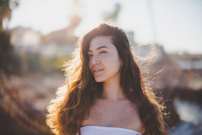 Portrait of smiling young woman standing against sky