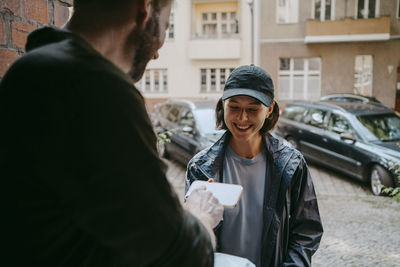 Smiling female delivery person taking electronic signature from customer while delivering courier