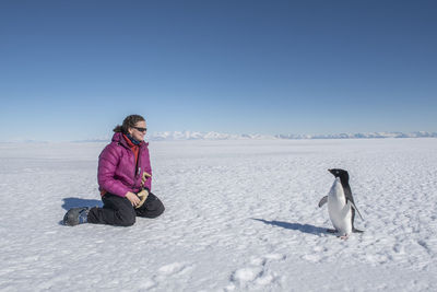 A woman has a close encounter with an adelie penguin in antarctica.