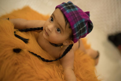 Close-up portrait of cute baby lying on bed at home