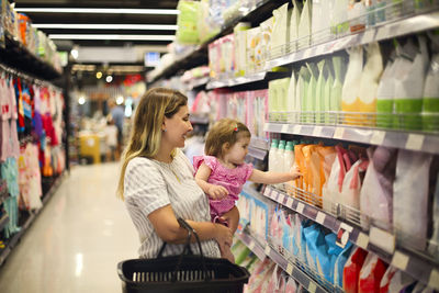 Smiling mother with daughter shopping at supermarket