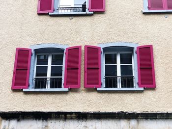 Low angle view of pink windows on wall of building