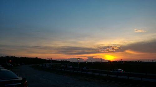 Vehicles parked on road at sunset