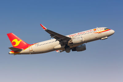 Low angle view of airplane flying against clear blue sky