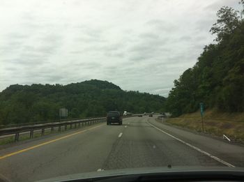 Cars on road against sky seen through car windshield