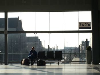 Woman with luggage sitting in lobby at railroad station