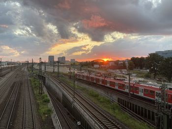 Railroad tracks in city against sky during sunset