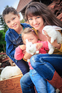 Portrait of smiling mother with daughters sitting outdoors