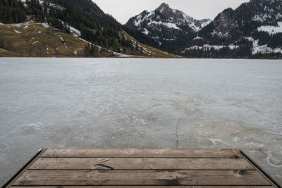 Scenic view of lake by snowcapped mountains against sky