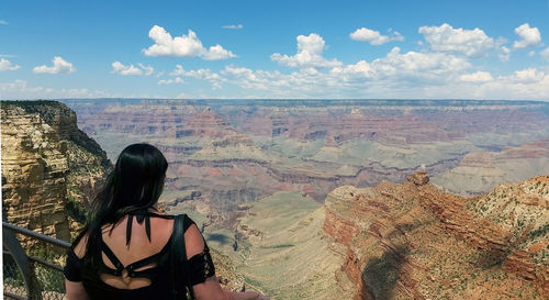 Rear view of woman looking at grand canyon against sky