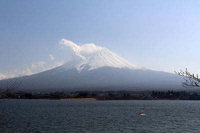 Scenic view of sea by snowcapped mountain against sky