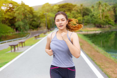 Portrait of smiling young woman standing on road