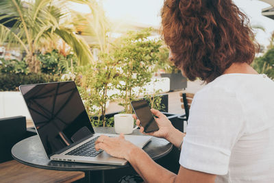 Midsection of woman using mobile phone while sitting on table