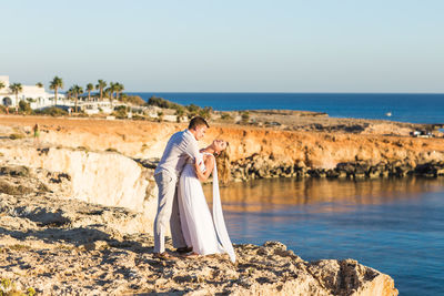 Woman on rock by sea against sky