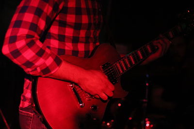 Midsection of man playing guitar