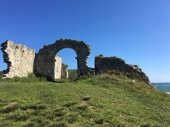 Castle by sea against clear blue sky