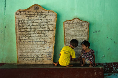 Rear view of women sitting against wall