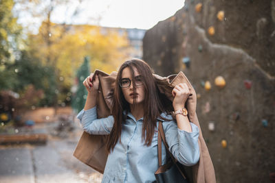 Portrait of young woman wearing jacket while standing against wall