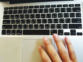 Cropped image of hand using laptop