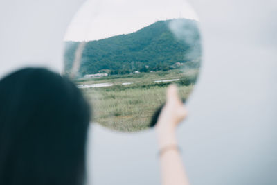 Midsection of person holding mountain against sky