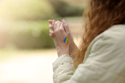 Stop war. peace in ukraine. woman hands with picture of flag of ukraine, hands folded in prayer. 