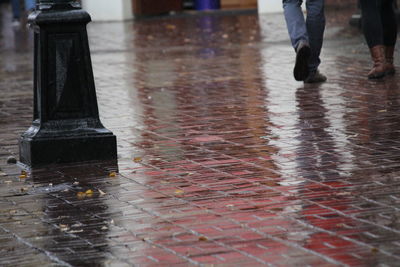 Low section of people standing on wet street