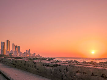 Scenic view of sea and buildings against sky during sunset