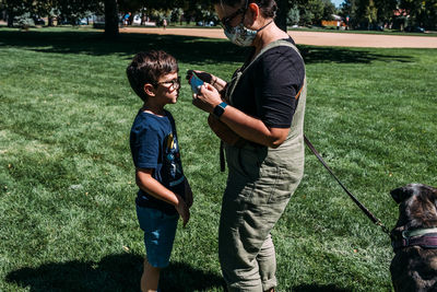 Mom helping young son put on facemark at park