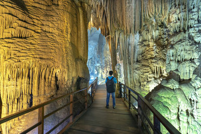 Rear view of woman standing in cave