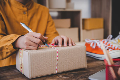 Midsection of woman writing on cardboard box