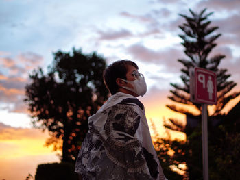 Side view of woman standing against sky during sunset