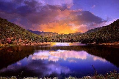 Scenic view of lake against dramatic sky at sunset