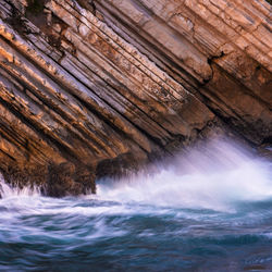 Beautiful schist cliff details in baleal island with ocean waves crashing in peniche, portugal