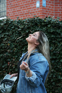 Side view of young woman standing against wall