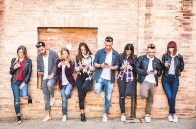 Group of people standing against brick wall