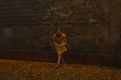 Portrait of young woman standing against brick wall