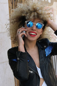 Smiling woman in sunglasses taking on mobile phone outdoors