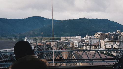 Rear view of man looking at cityscape against sky