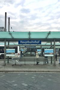 Man standing at bus stop against sky