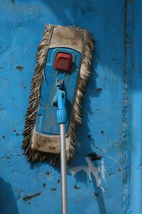 Abandoned mop against blue wall