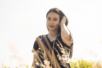 Portrait of young woman standing against clear sky