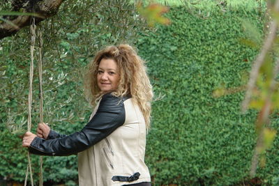 Portrait of a beautiful young woman standing against plants