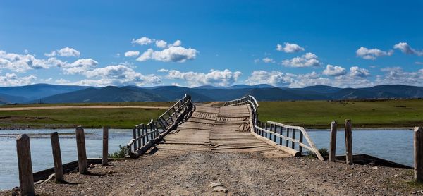 Wooden fence by mountains against sky