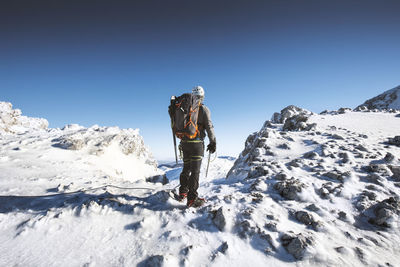 Rear view of man standing on snow covered mountain